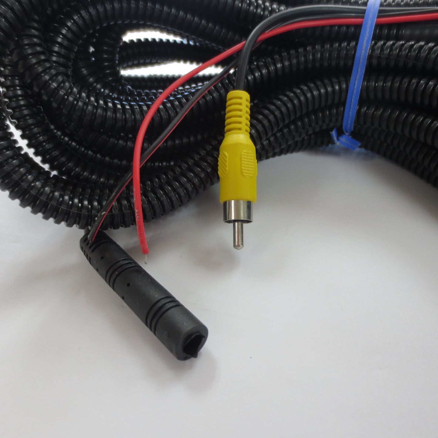 Coiled black cable with red wires and a yellow connector background