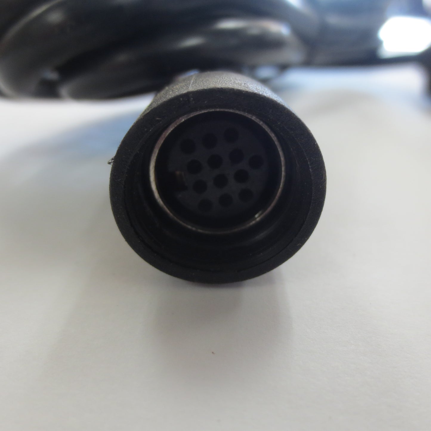 Close-up of a black connector with multiple holes on a white surface