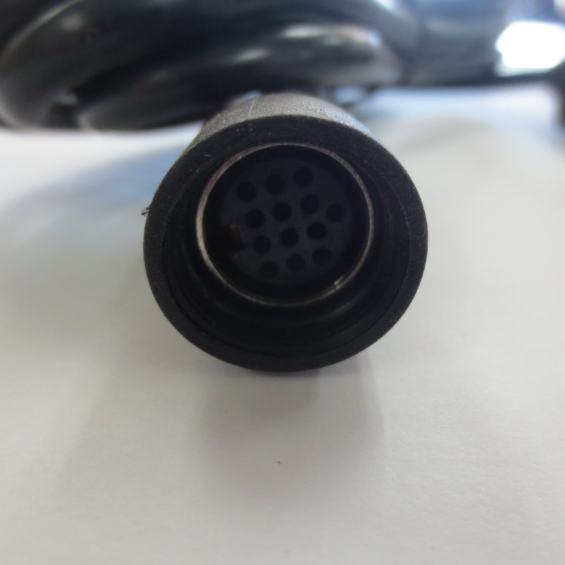 Close-up of a black connector with multiple holes on a white surface