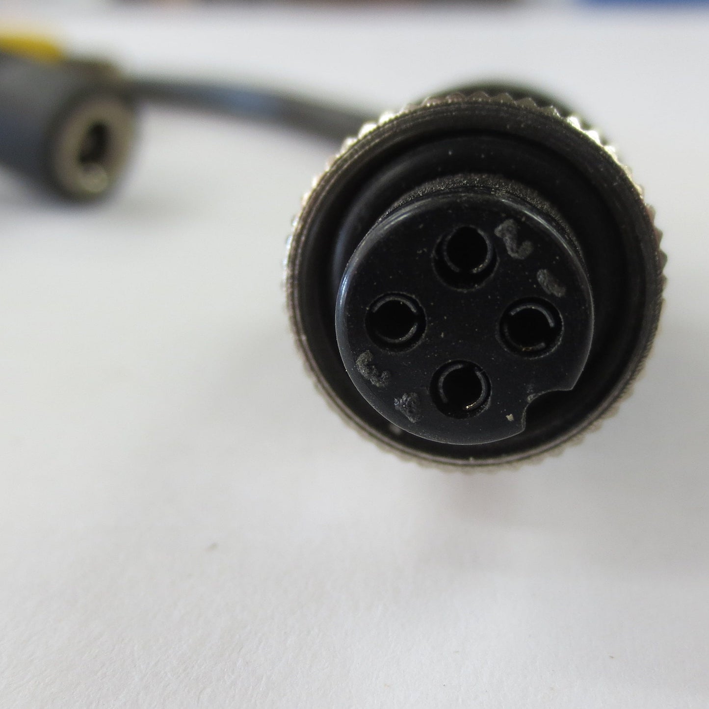 Close-up of a black cylindrical connector on a white surface with blurred background