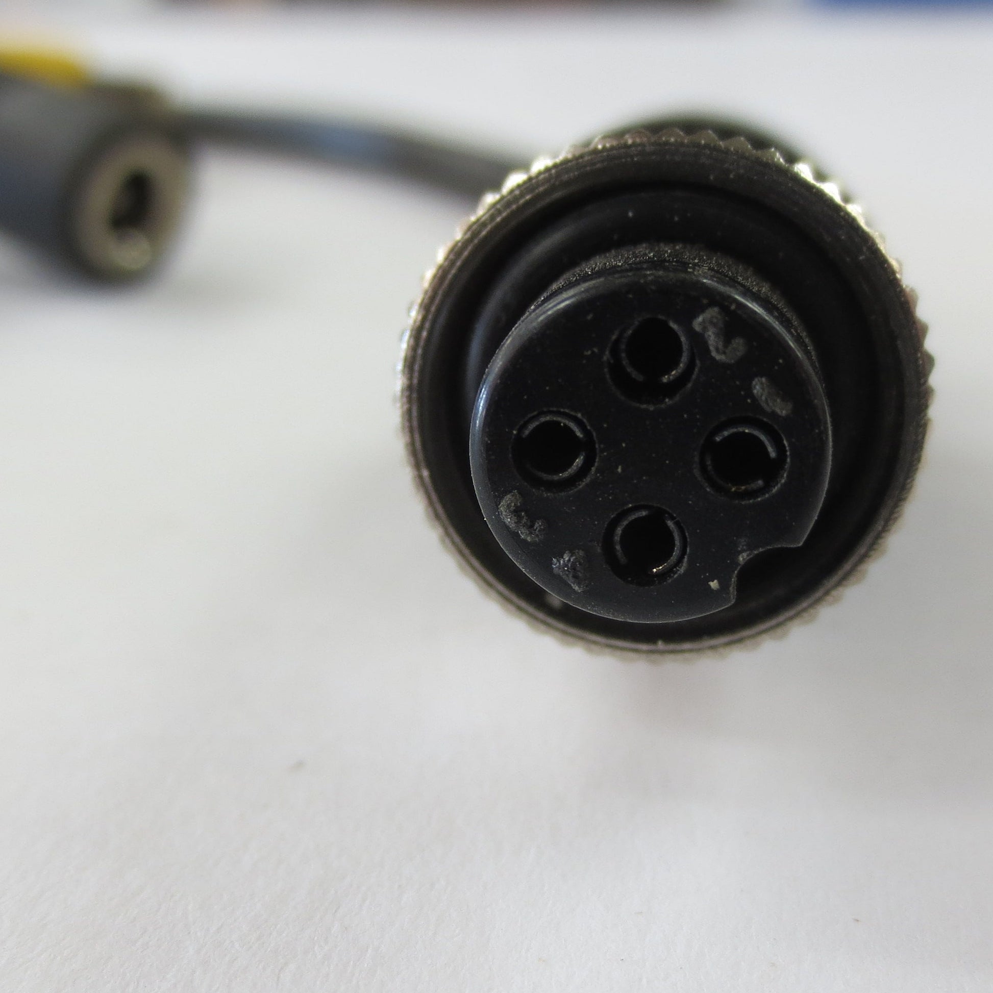 Close-up of a black cylindrical connector on a white surface with blurred background