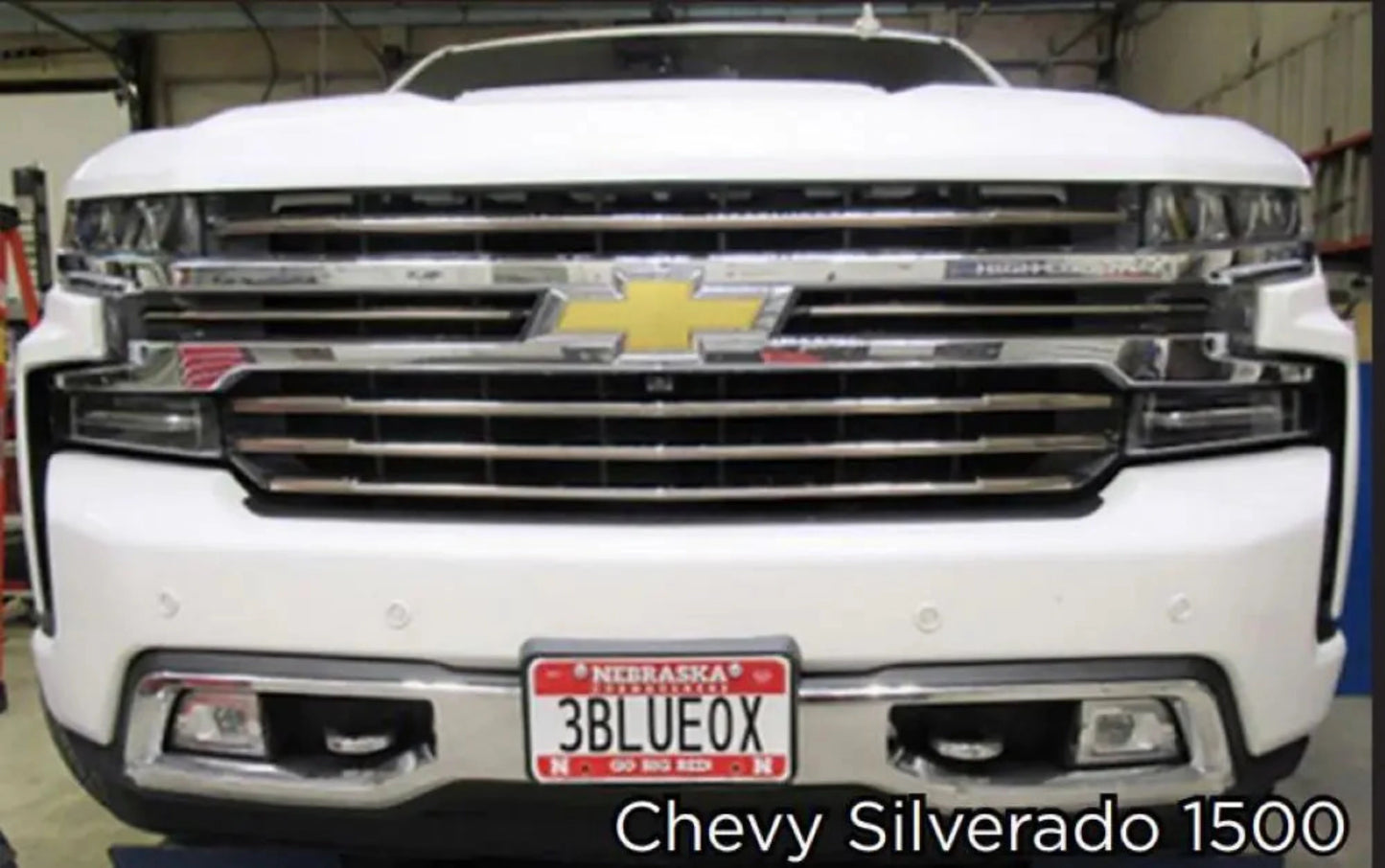 Front view of a white Chevrolet Silverado 1500 truck in a garage with Blue Ox Base plate.
